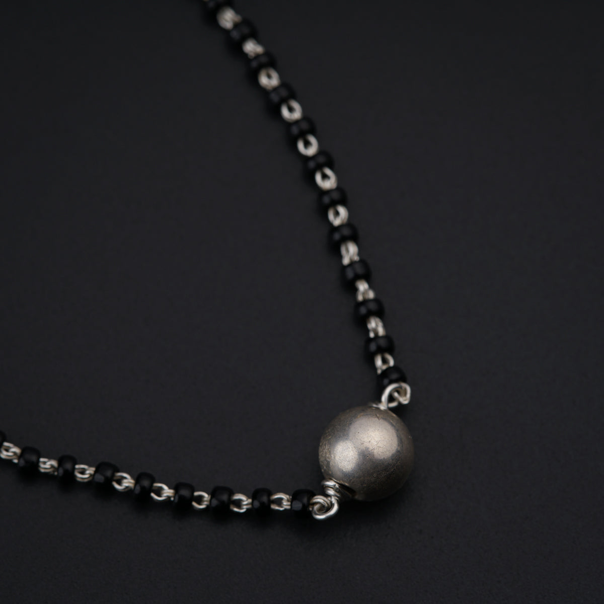 a black and silver necklace with a ball on it