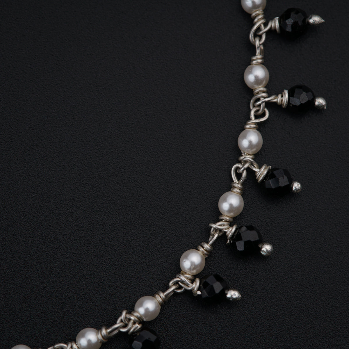 a close up of a necklace with pearls and black beads