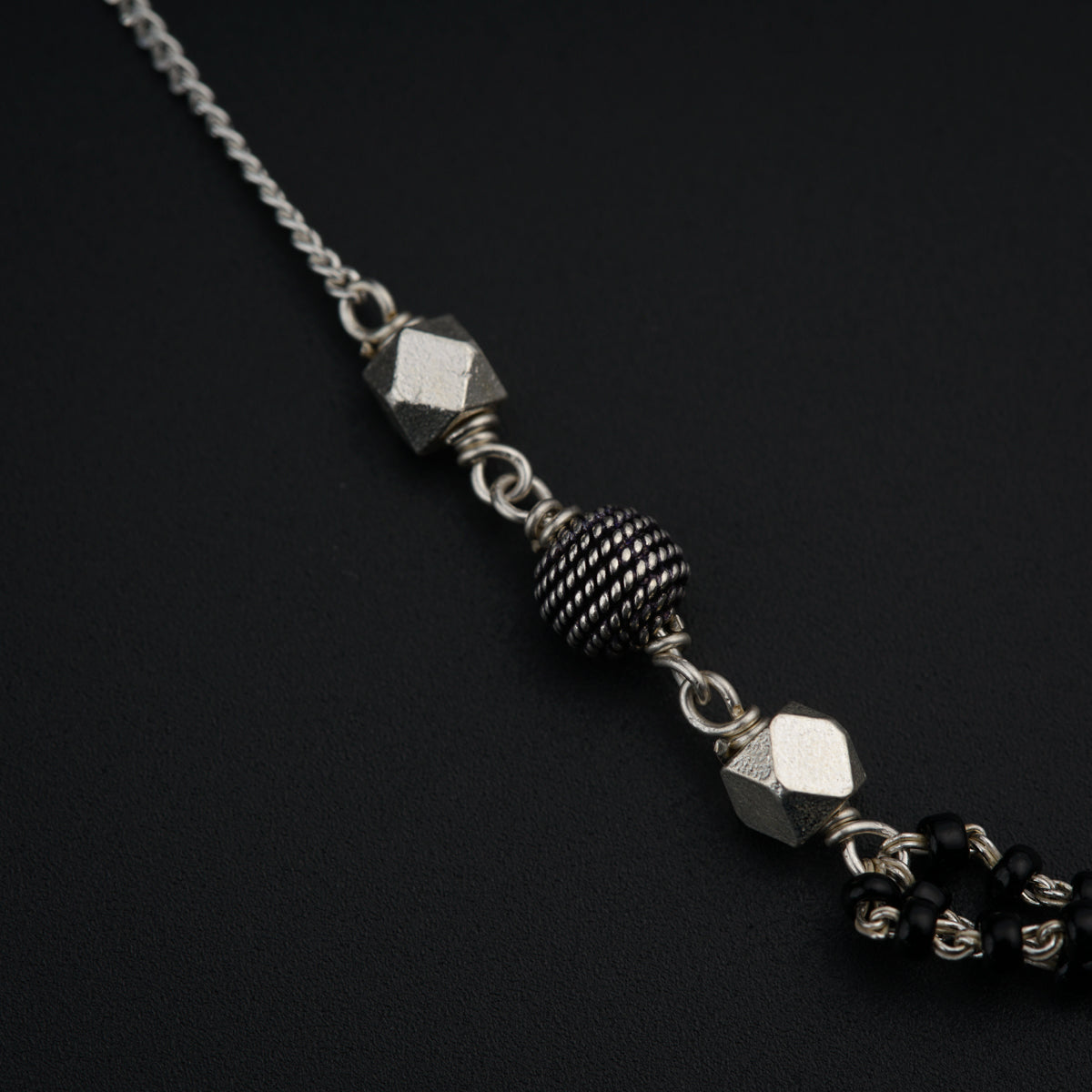 a silver chain with a black bead on it