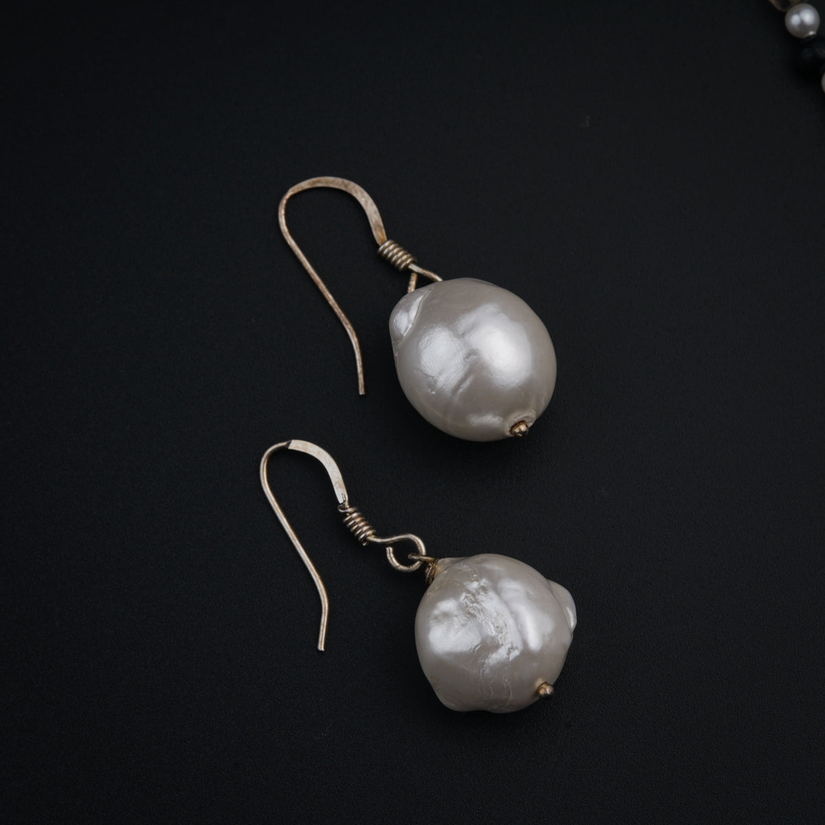 a pair of pearl earrings on a black background