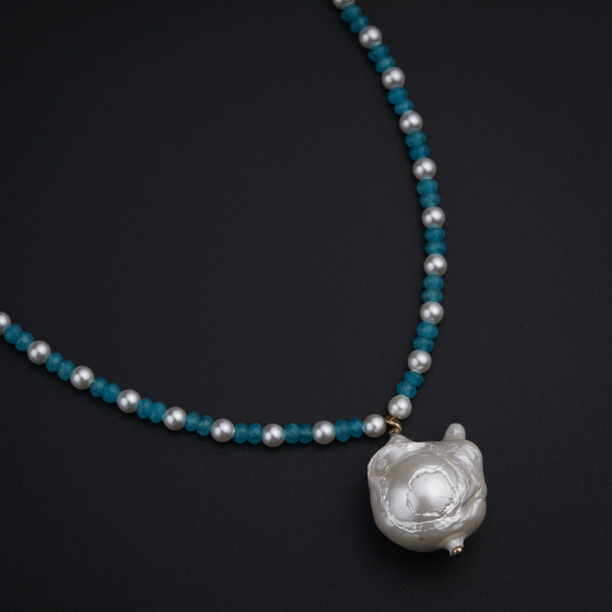a necklace with a white flower and blue beads