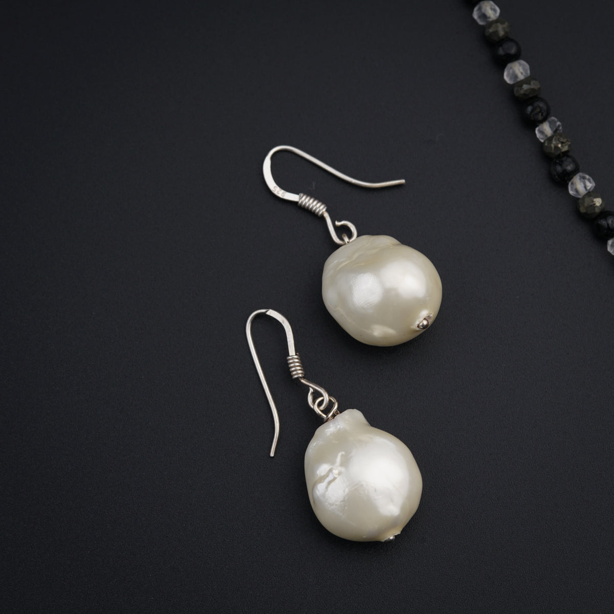a pair of white pearls are hanging from a necklace