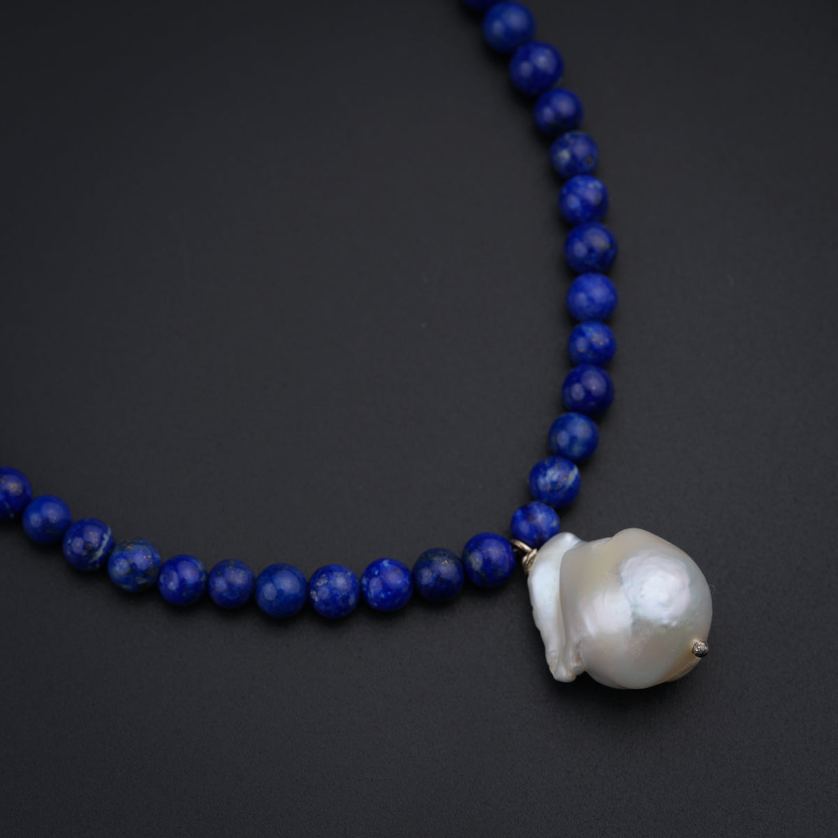 a blue beaded necklace with a white shell on it