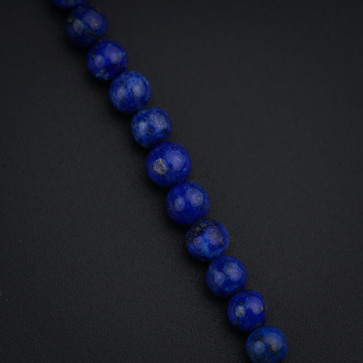 a close up of a blue bead on a black surface