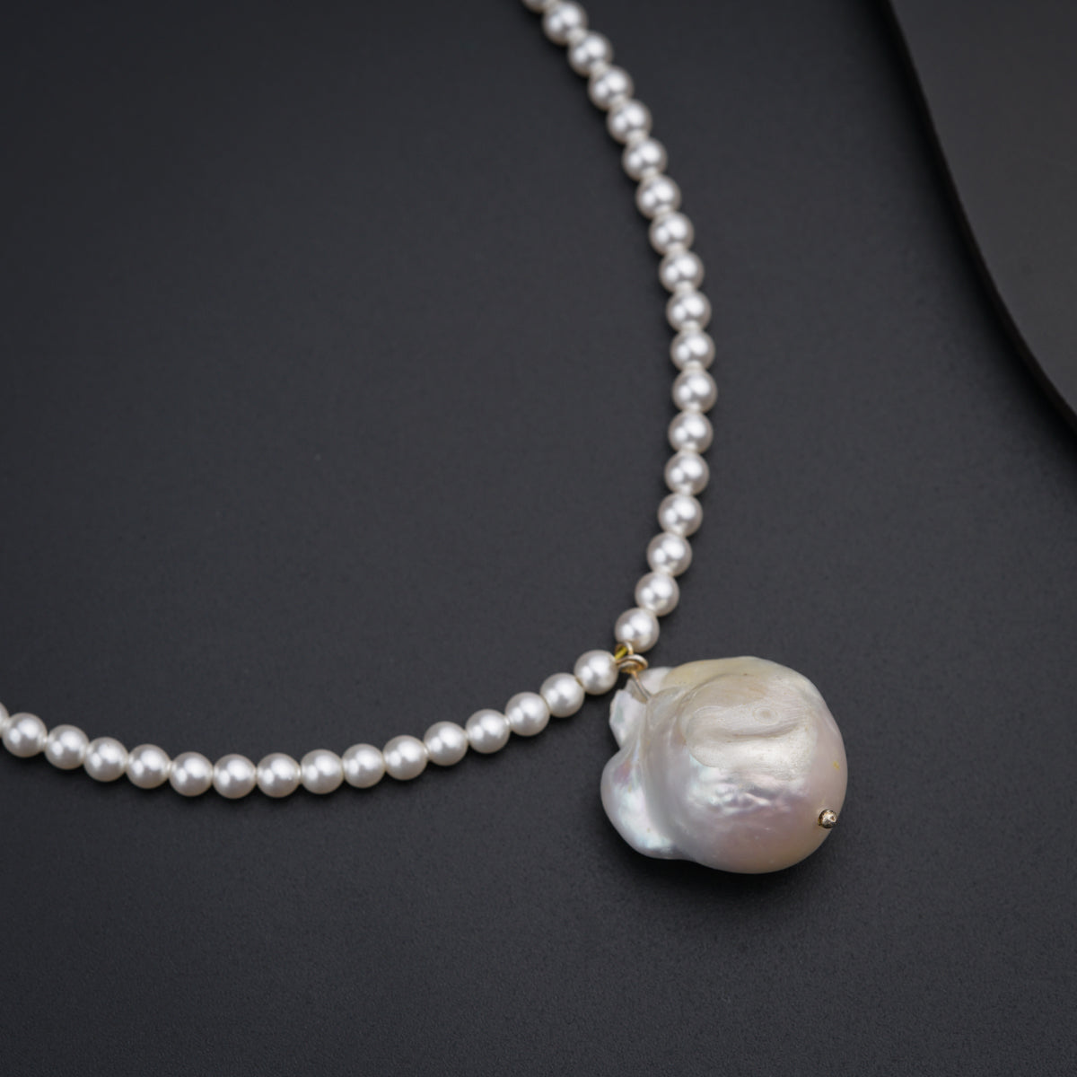 a necklace with a white pearl and a gold clasp