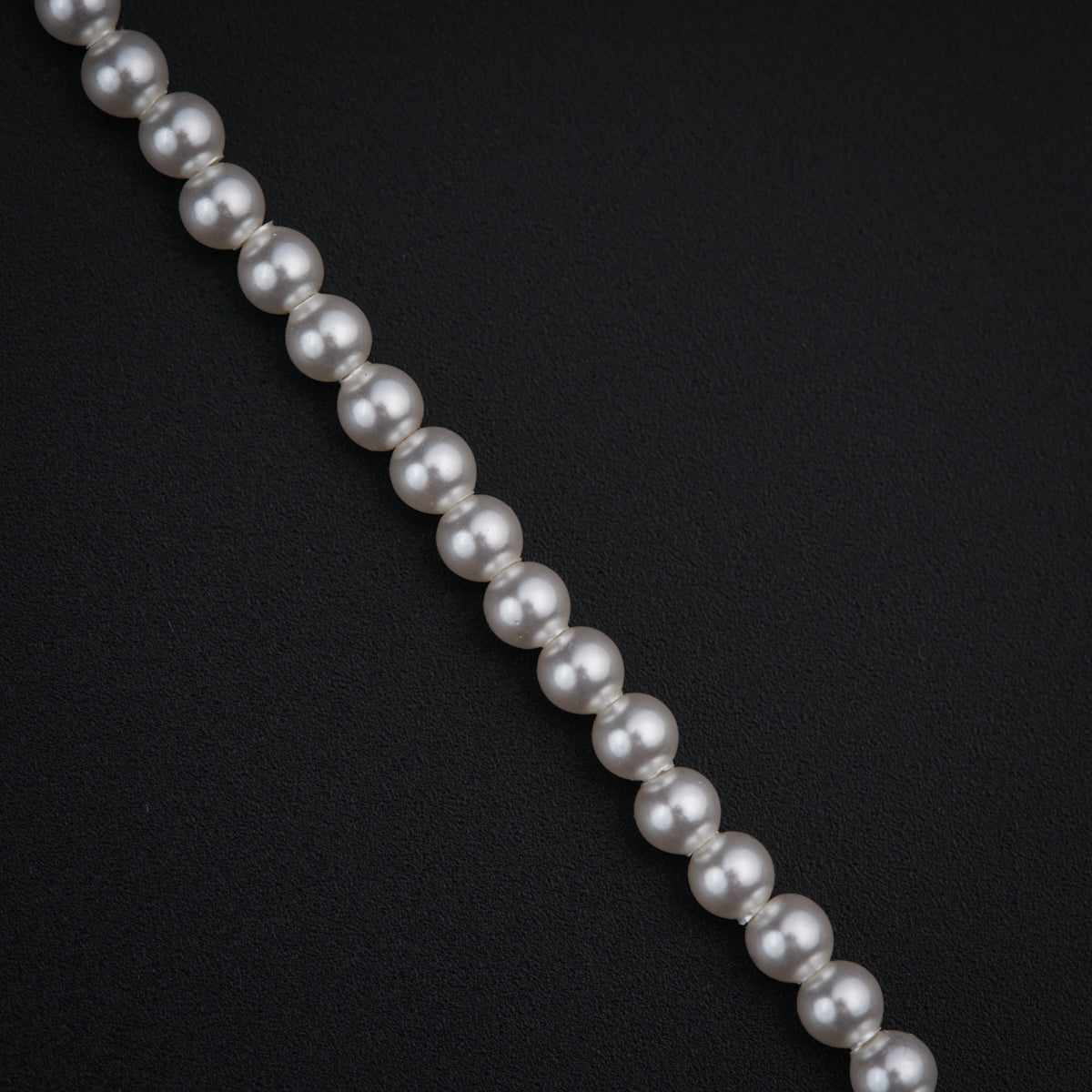 a long strand of white pearls on a black background