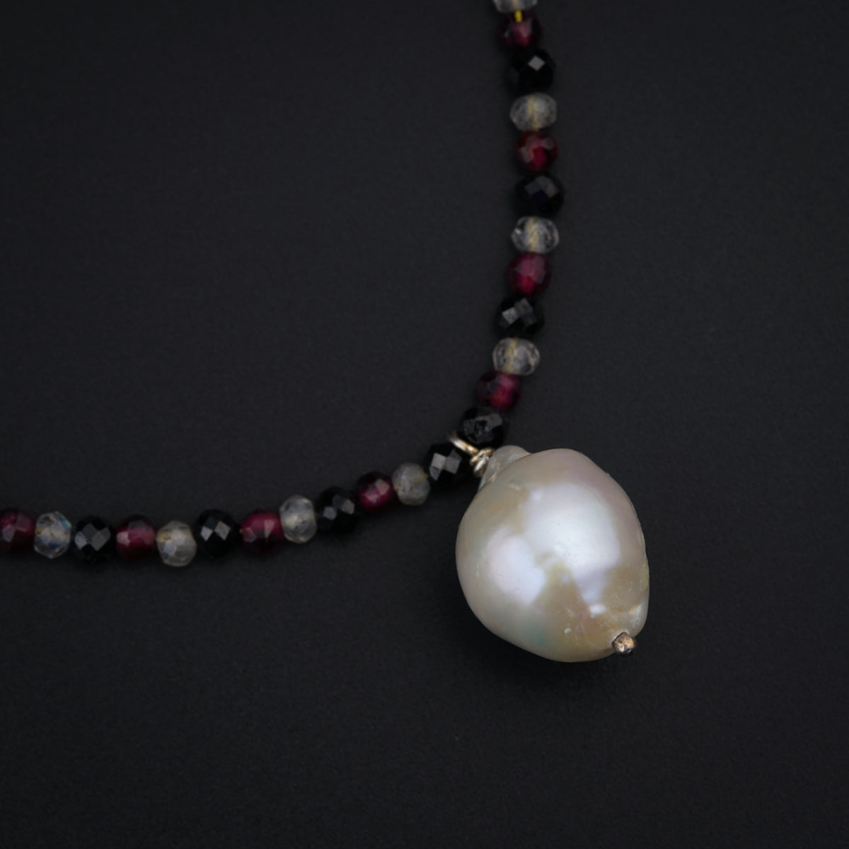 a necklace with a large white pearl on a black background