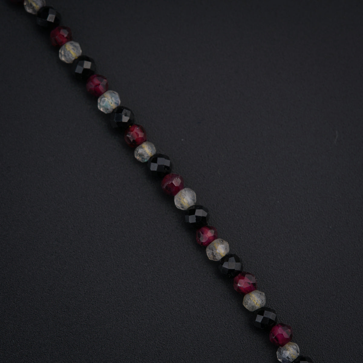 a close up of a beaded necklace on a black surface