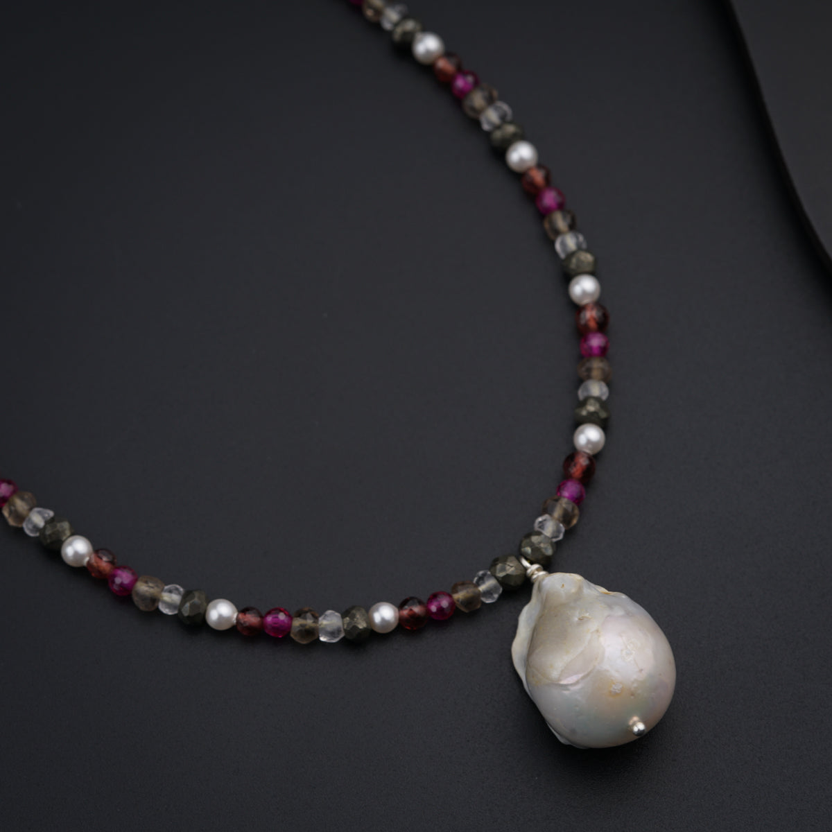 a necklace with a shell on a black surface