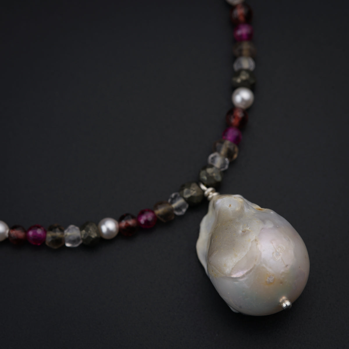 a necklace with a shell and beads on a black surface