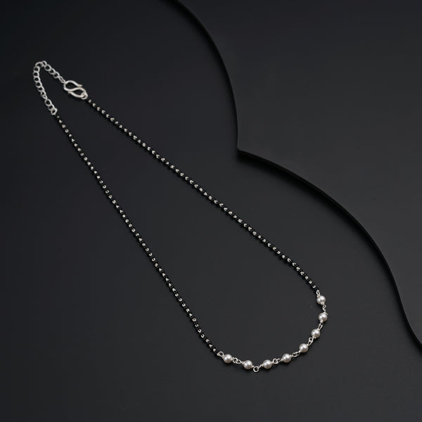 a black and white necklace on a black surface