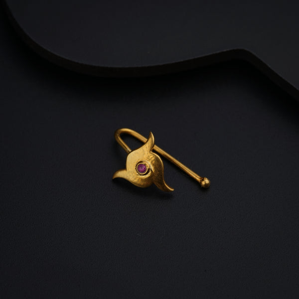 a gold brooch with a pink stone in the center