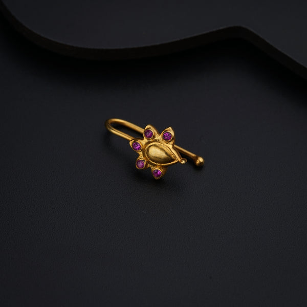 a gold brooch with pink stones on a black background