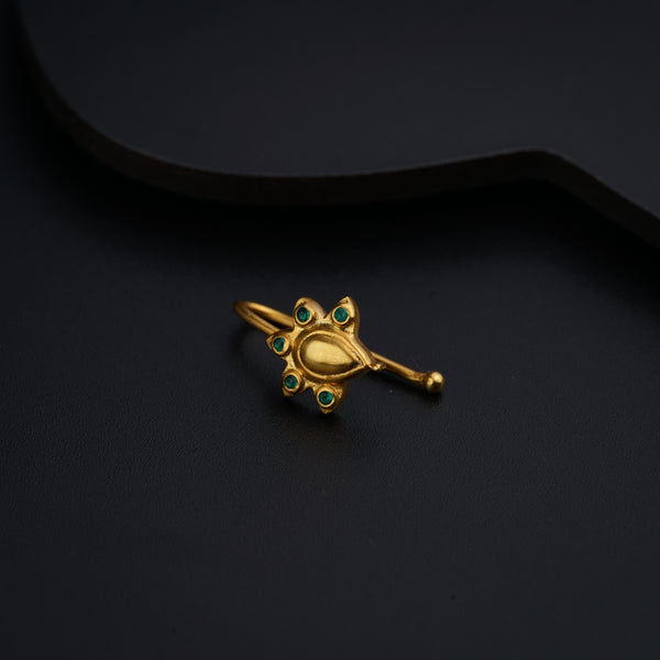 a gold brooch with green stones on a black background