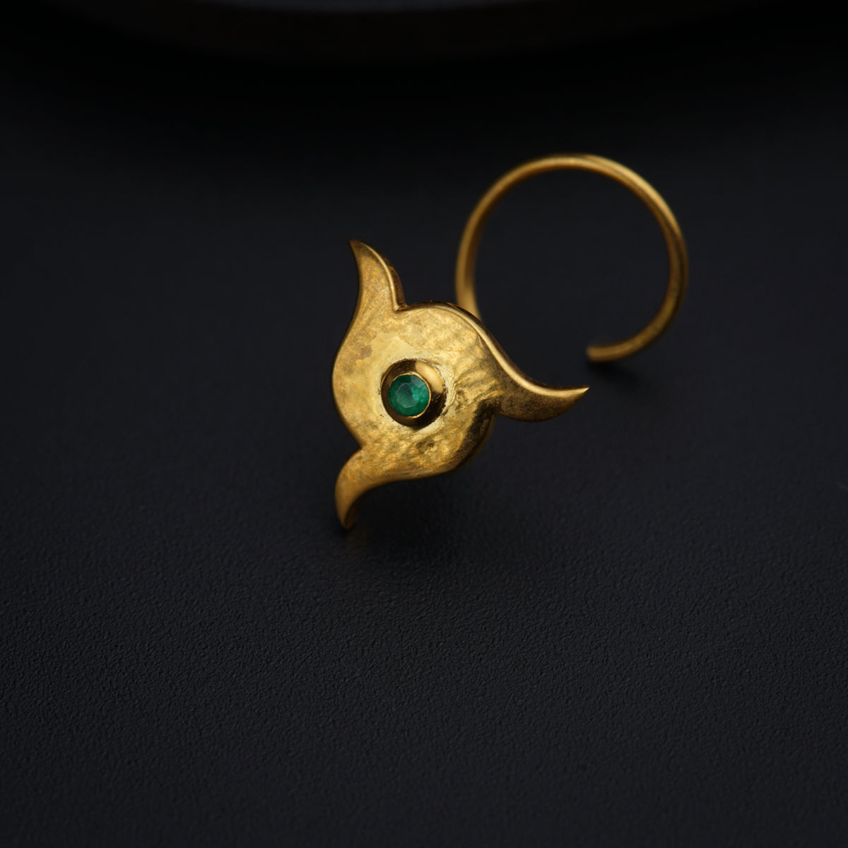 a close up of a gold ring with a green stone