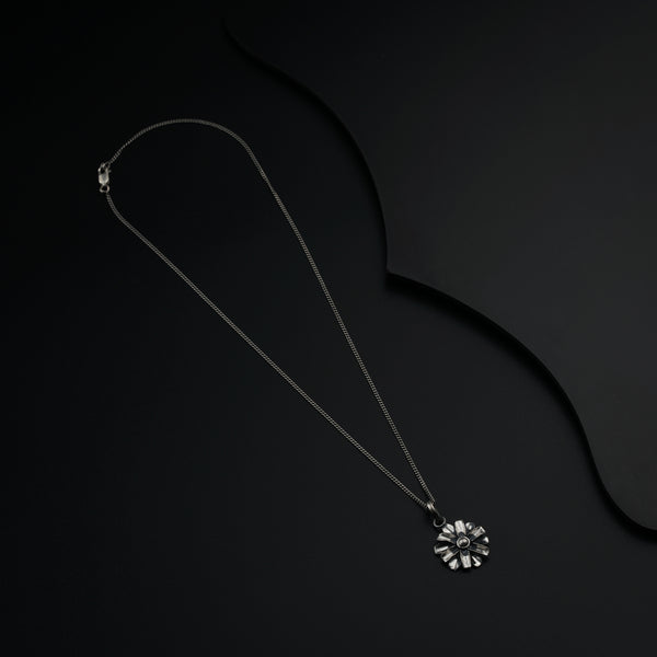 a necklace with a flower on a black background