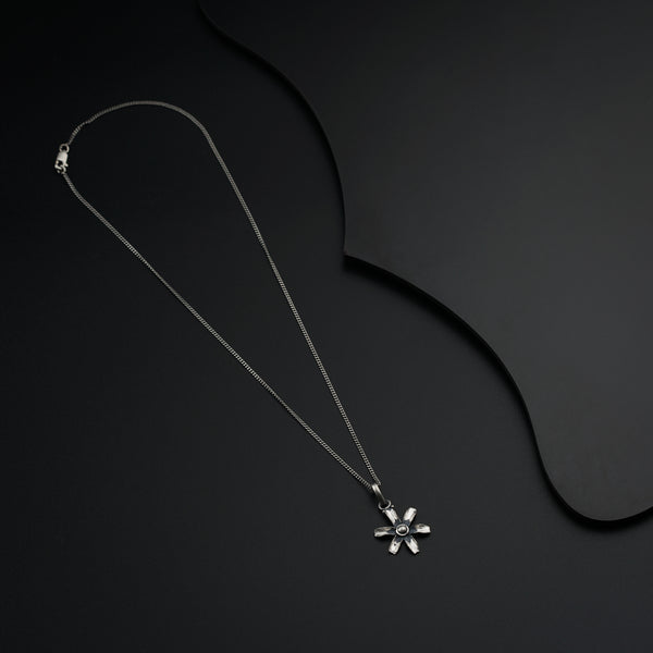 a necklace with a flower on a black background