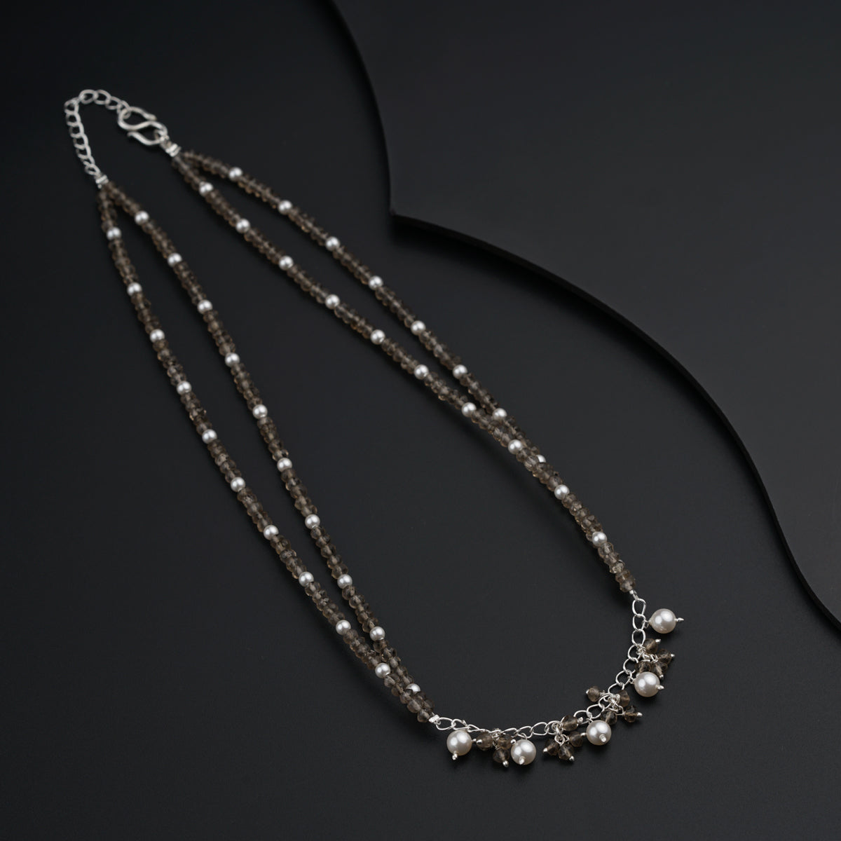 a long necklace with pearls and beads on a black surface