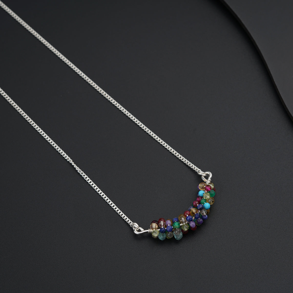 a silver necklace with a multi colored bead on it