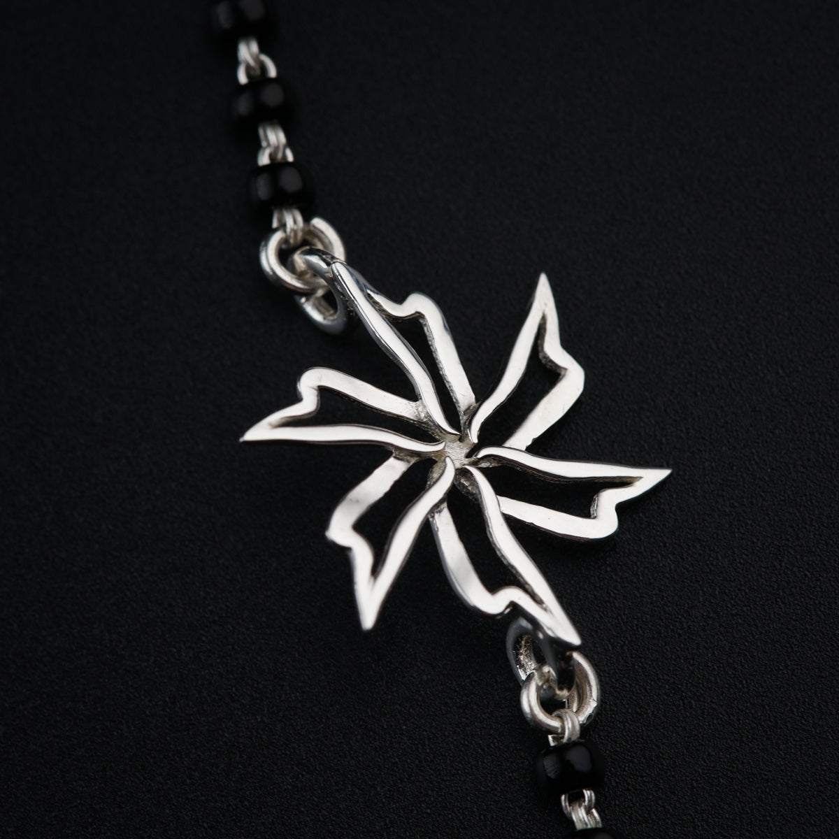 a silver cross on a chain on a black background