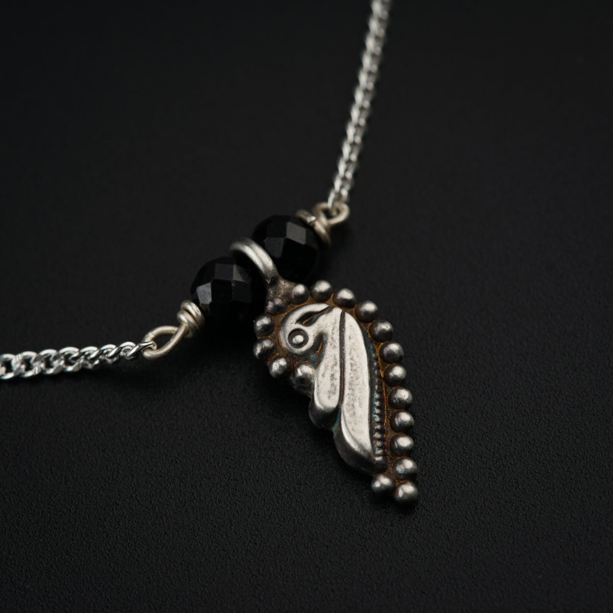 a black and silver necklace with a horse head on it