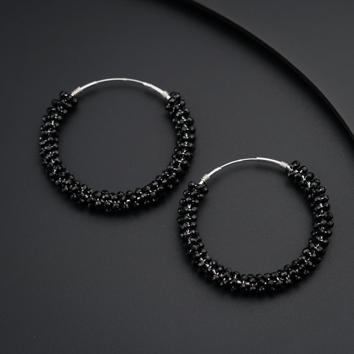 a pair of black beaded hoop earrings