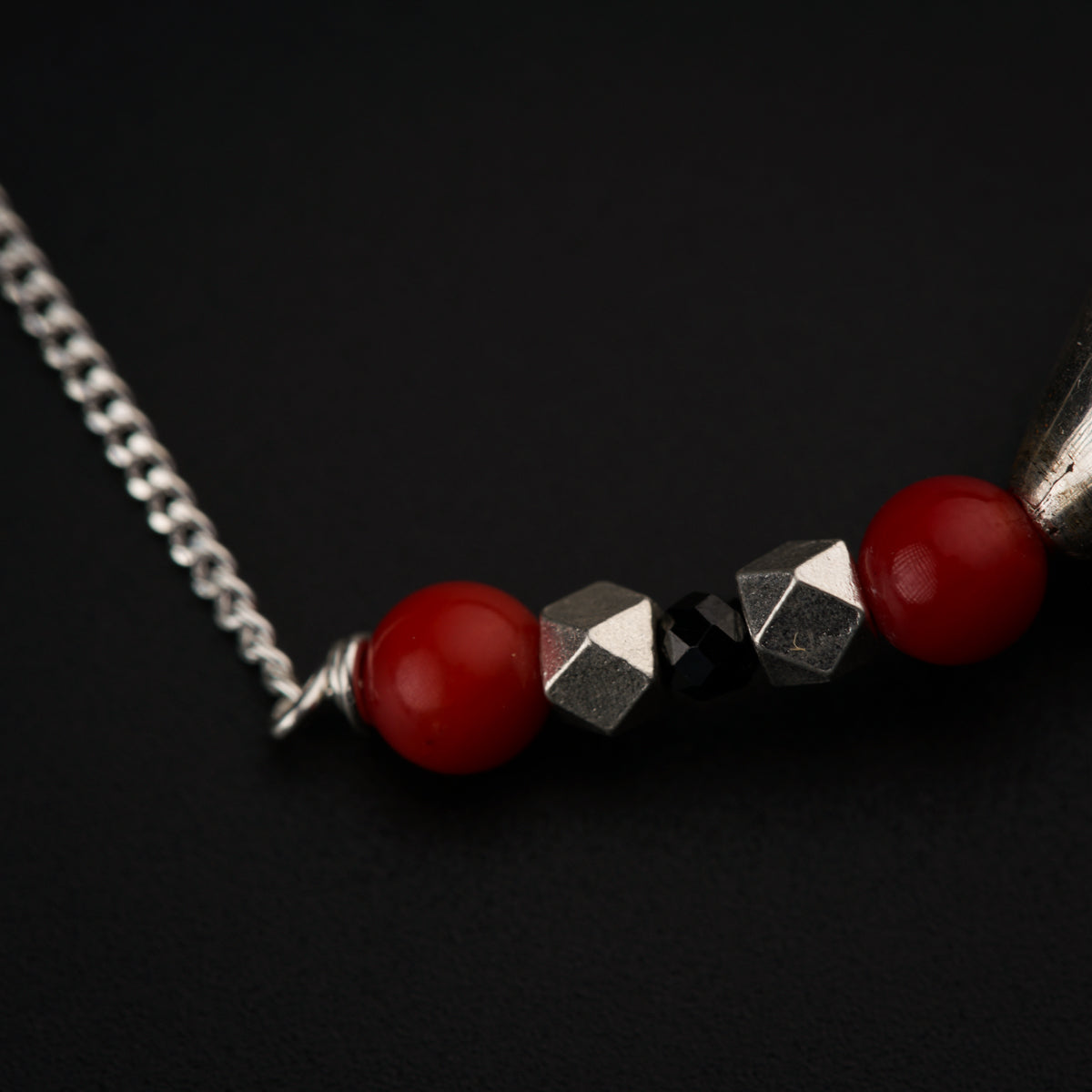 a red bead and silver chain on a black surface