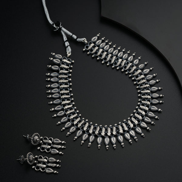 a silver necklace and matching earrings on a black surface