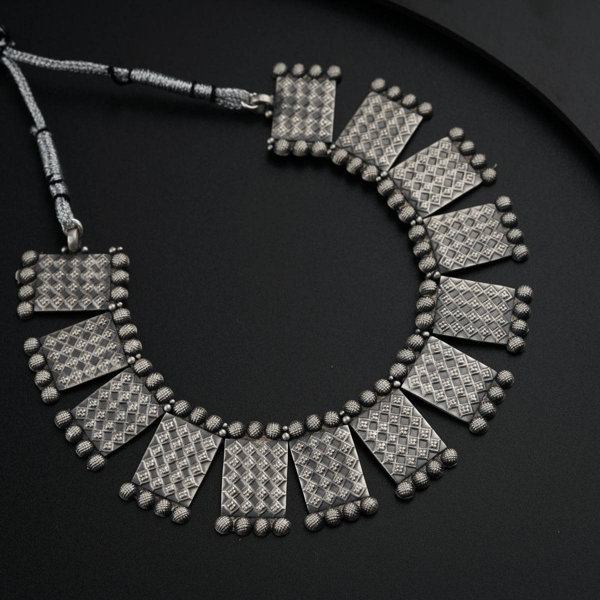 a necklace made of silver beads on a black surface