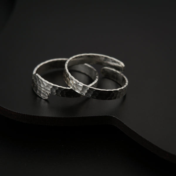 Angled side view of silver hammered toe ring showing adjustable band and reflective surface