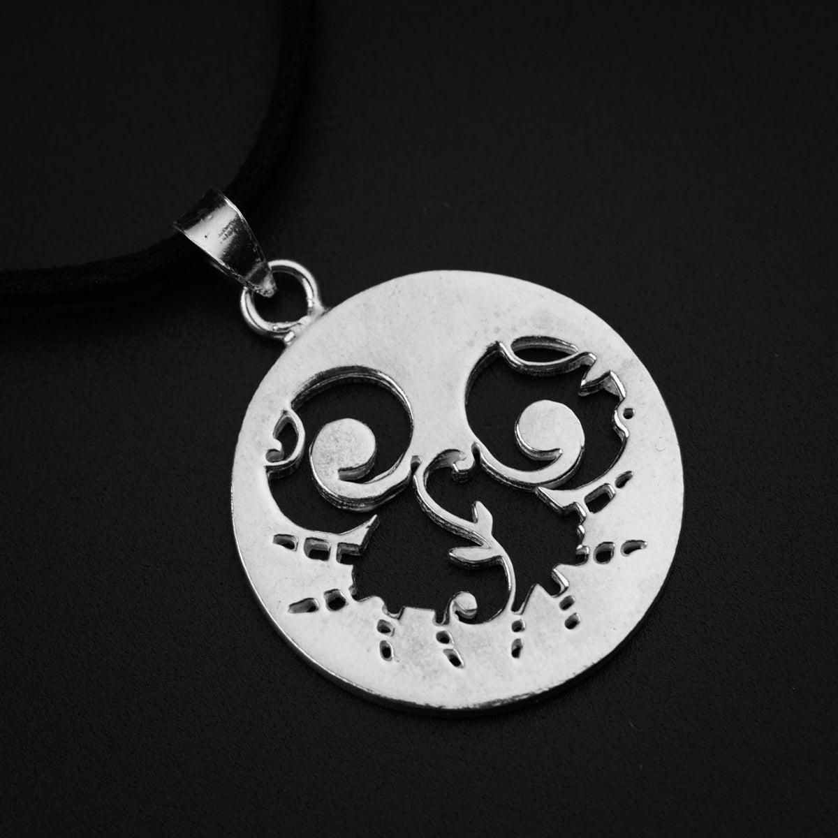 a silver pendant with a face on a black background