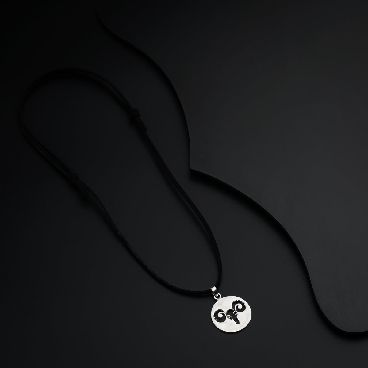 a black and white photo of a necklace with a skull on it