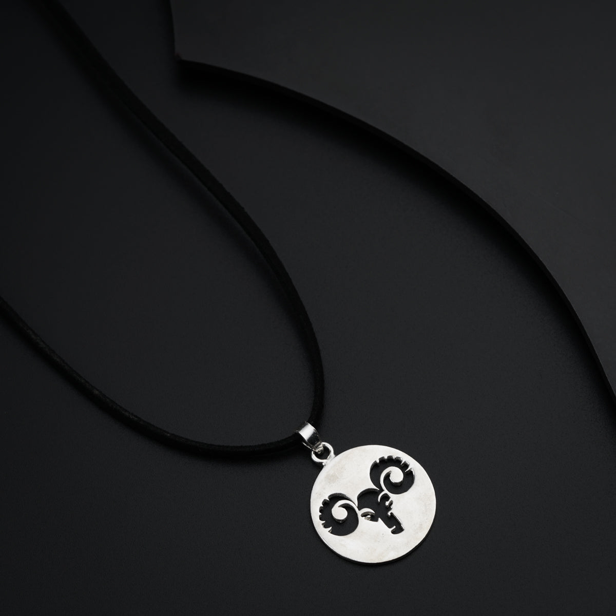 a black and white photo of a necklace with a skull on it