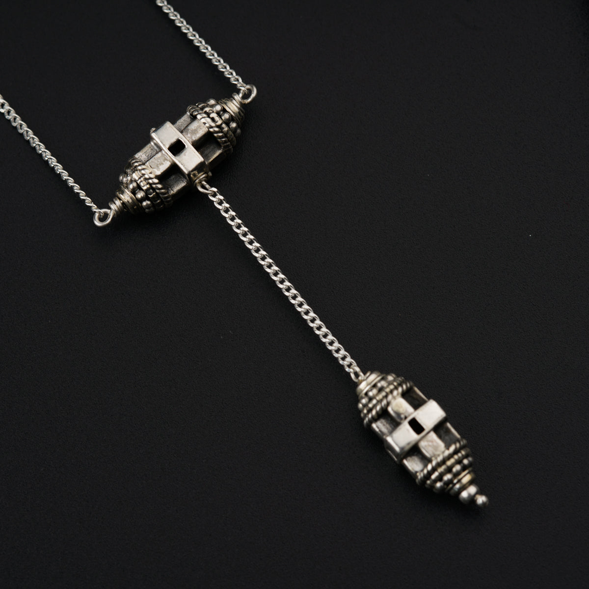a pair of silver toned necklaces on a black surface