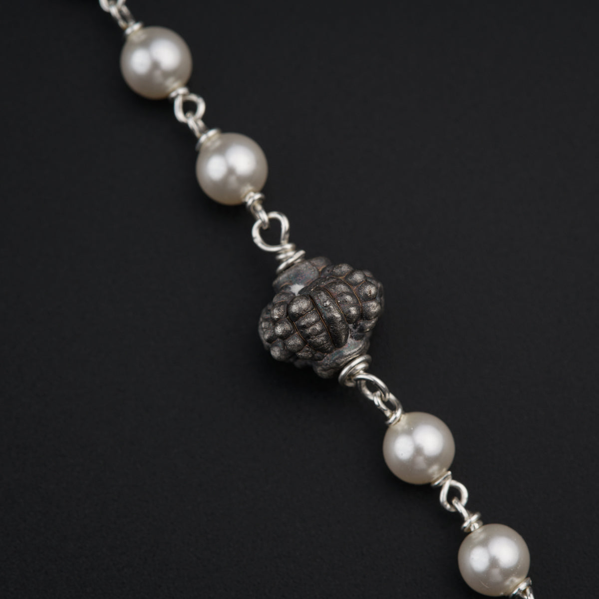 a bracelet with pearls on a black background