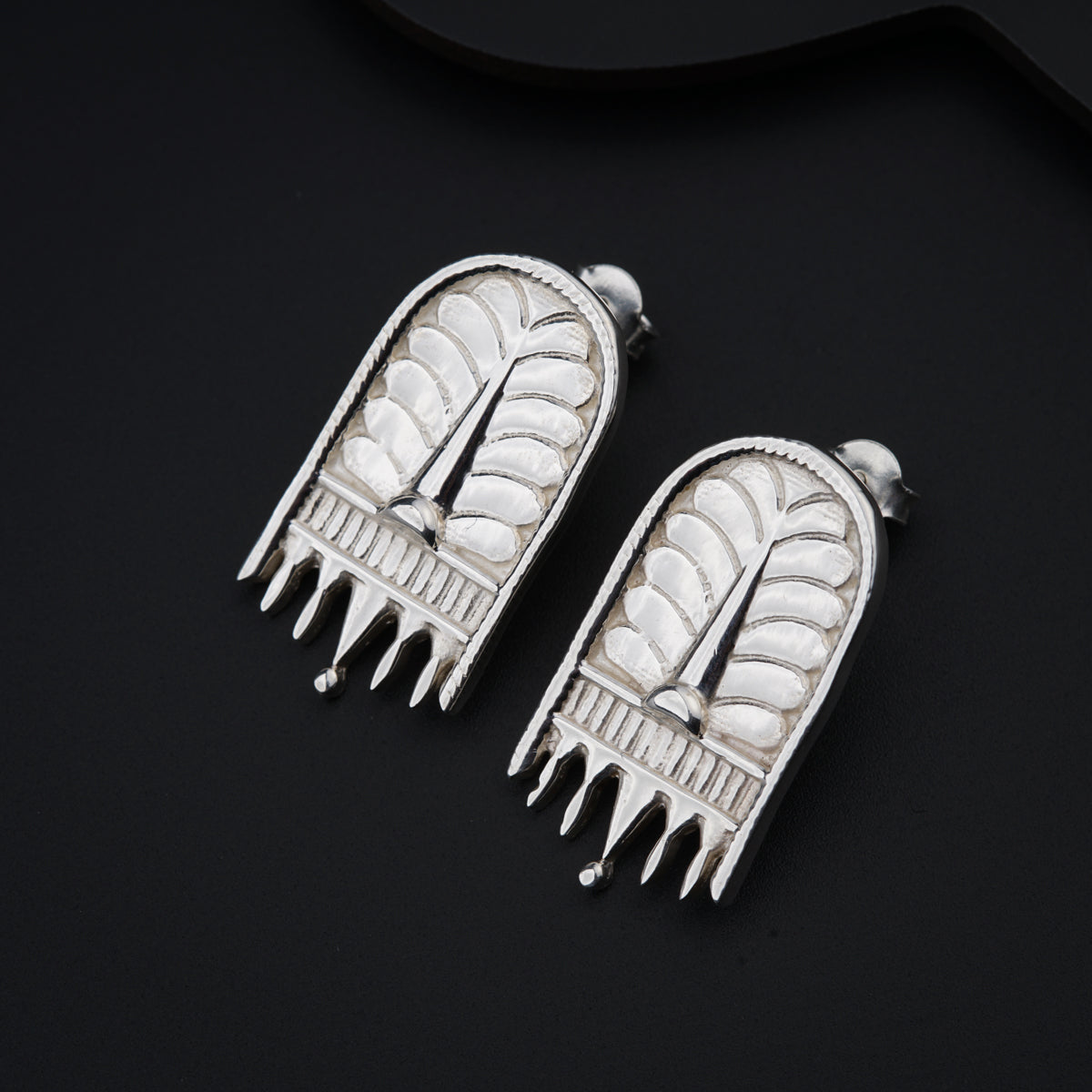 a pair of silver colored earrings on a black surface