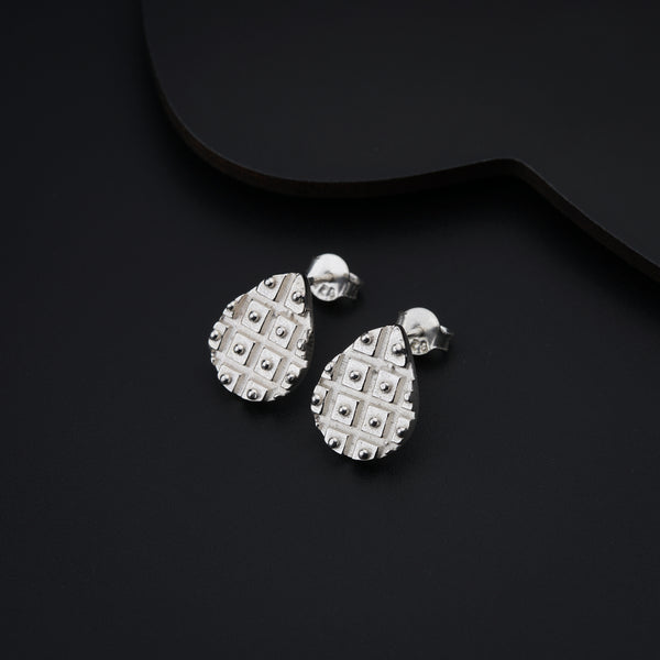 a pair of earrings sitting on top of a black surface