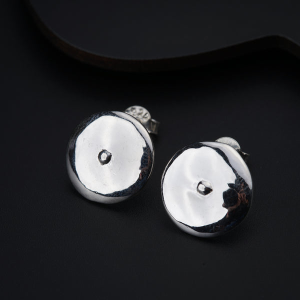 a pair of silver earrings sitting on top of a black surface