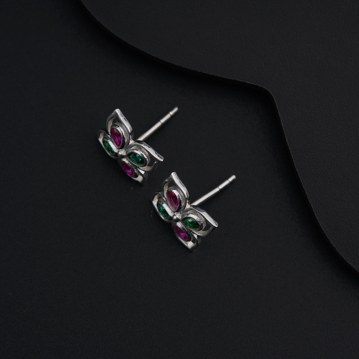a pair of silver earrings with pink and green stones
