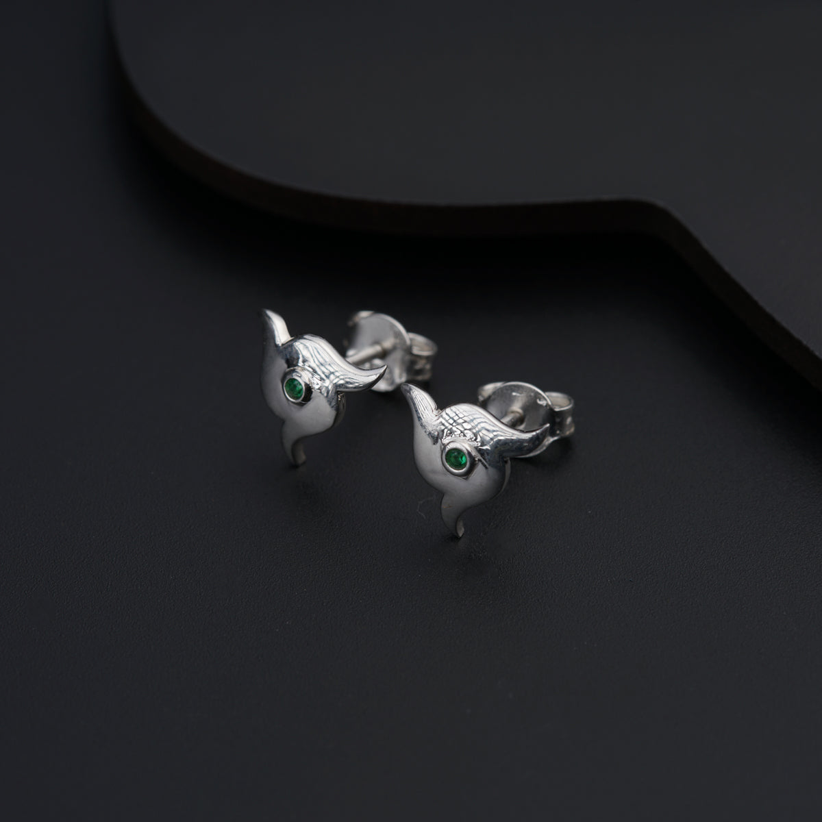 a pair of silver bird earrings with green eyes