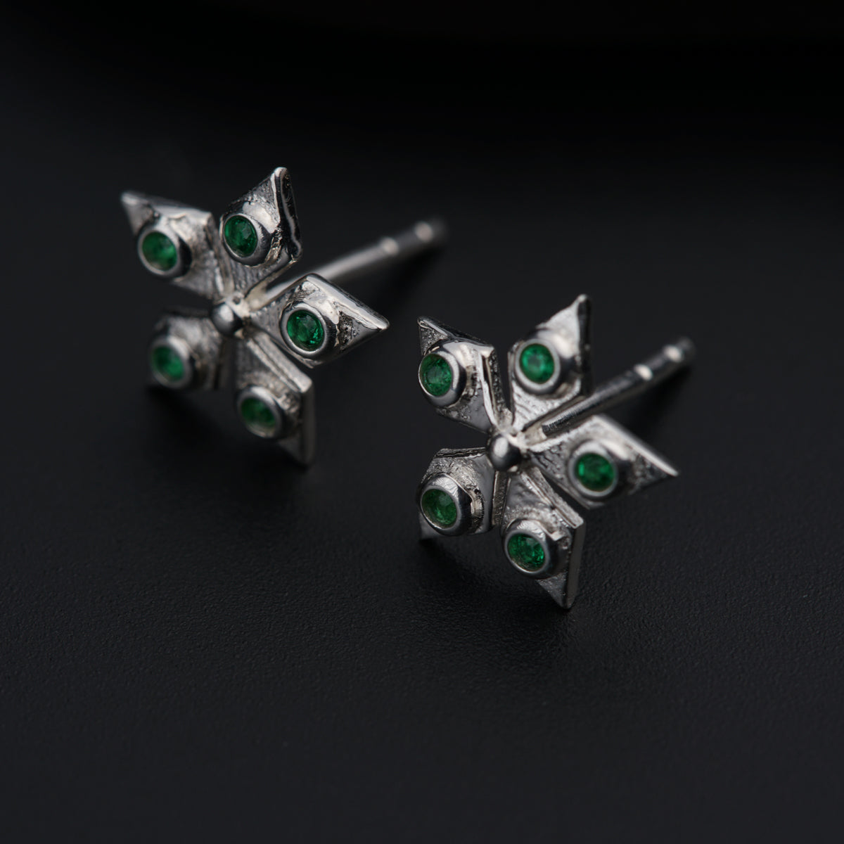 a pair of silver earrings with green stones