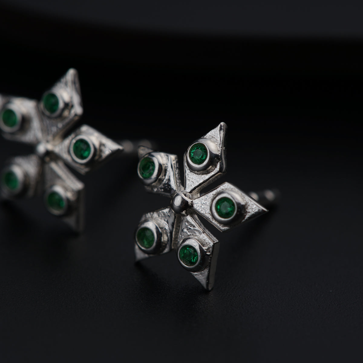 a pair of silver earrings with green stones