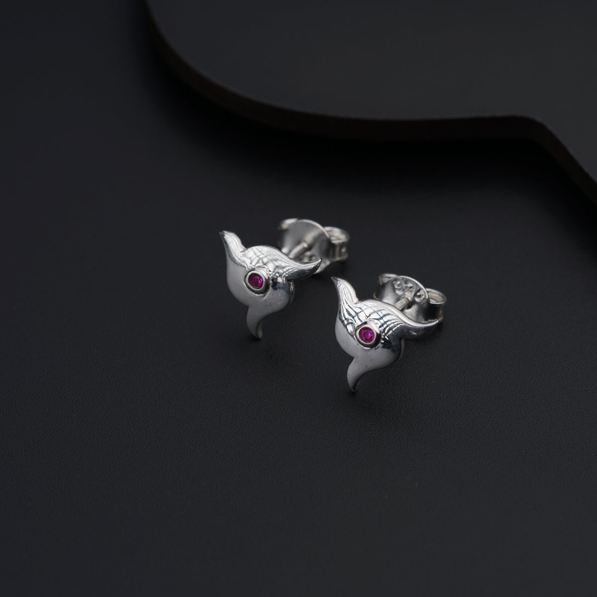 a pair of silver fish earrings with pink stones