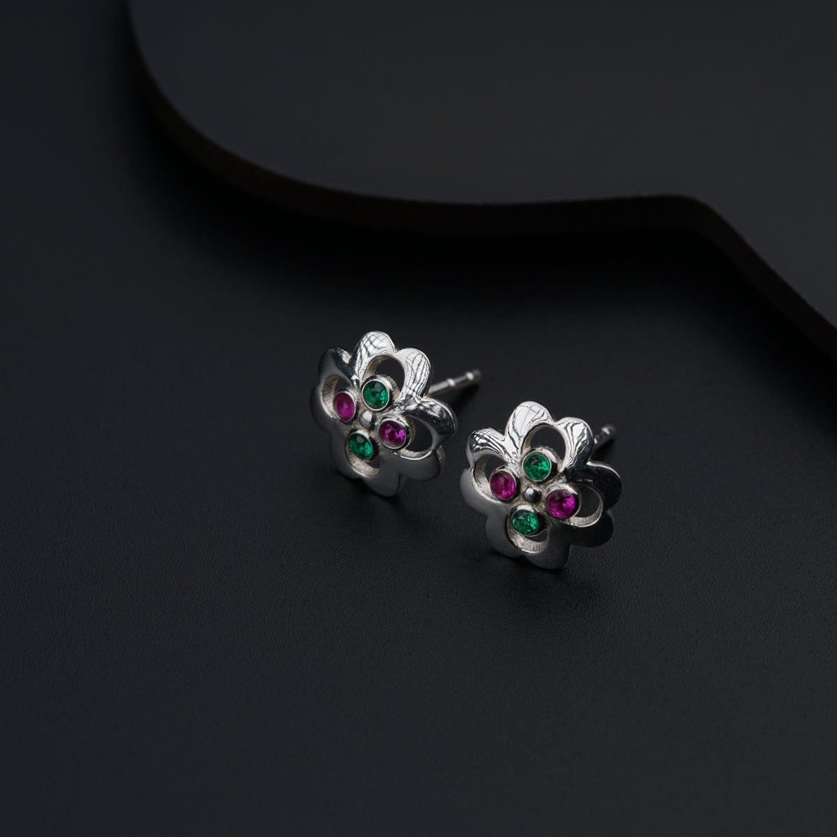 a pair of silver earrings with green and pink stones