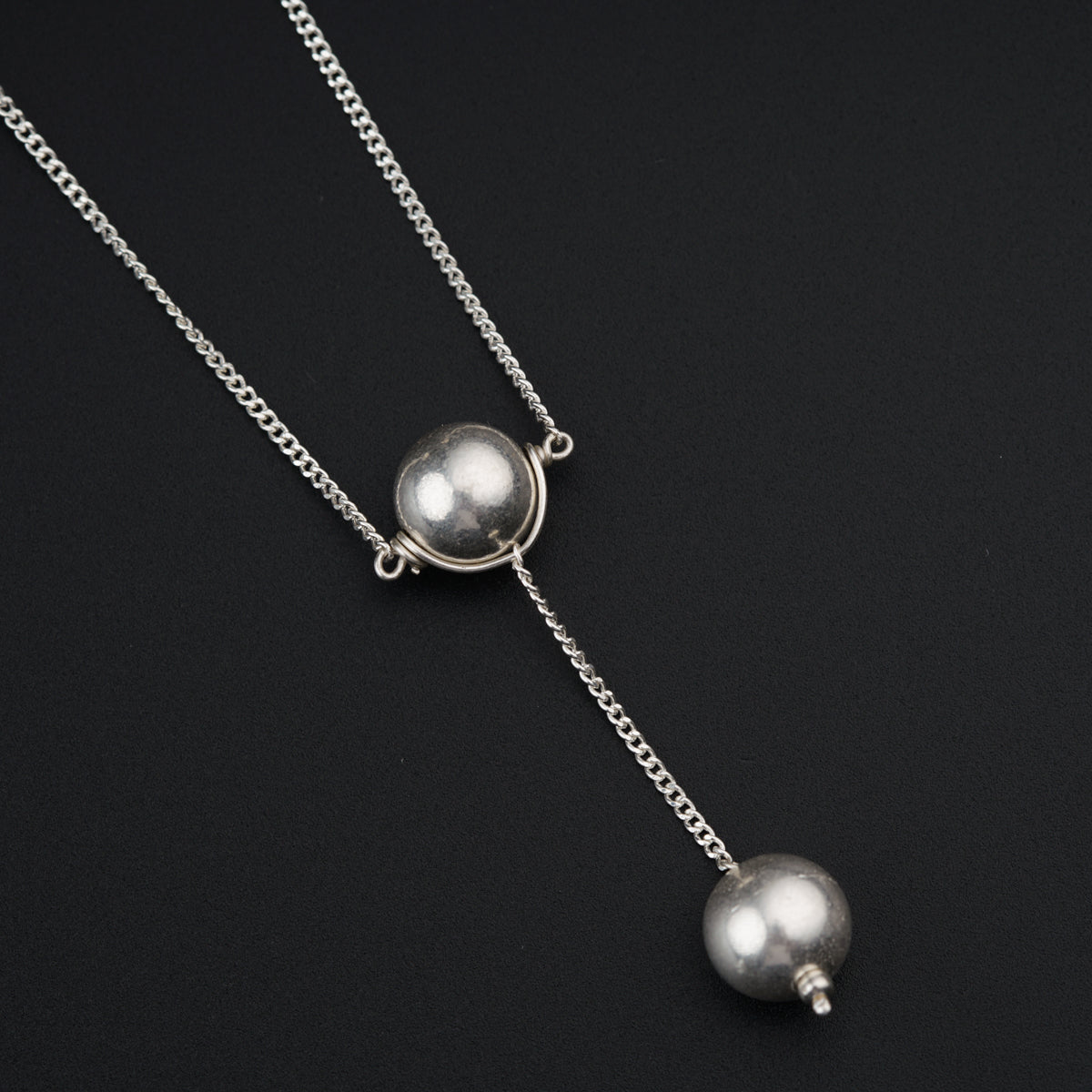 a silver necklace with two balls hanging from it