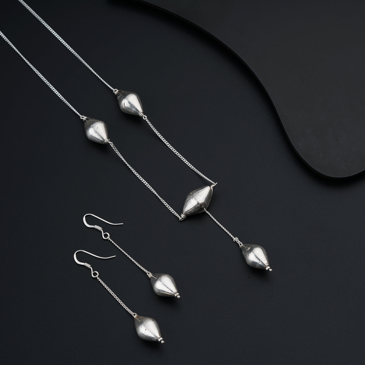 a set of silver jewelry on a black surface
