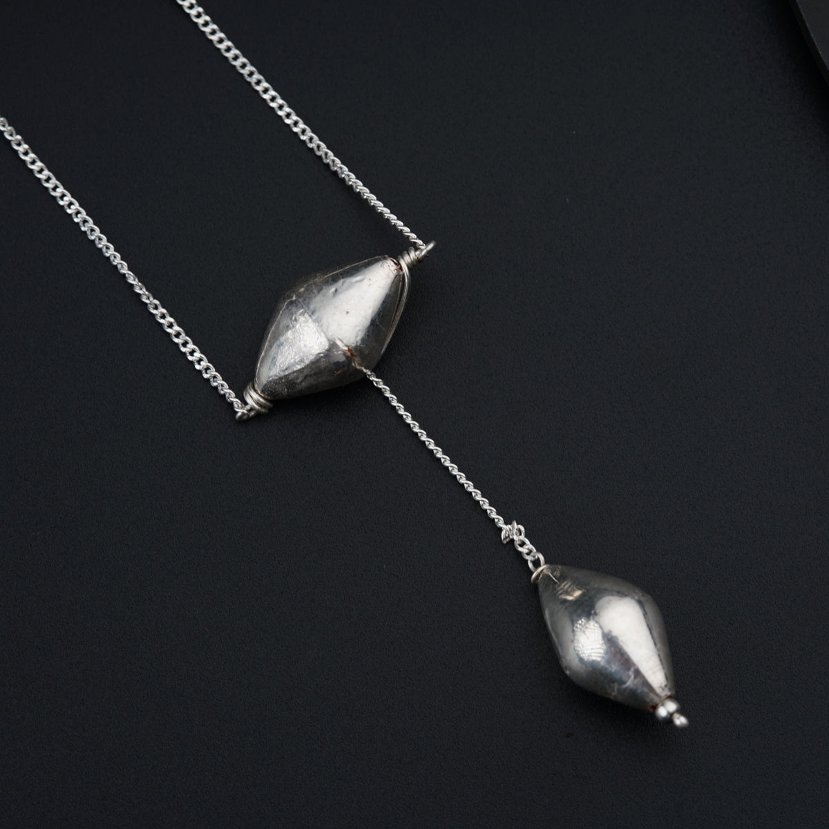 a couple of silver necklaces sitting on top of a table