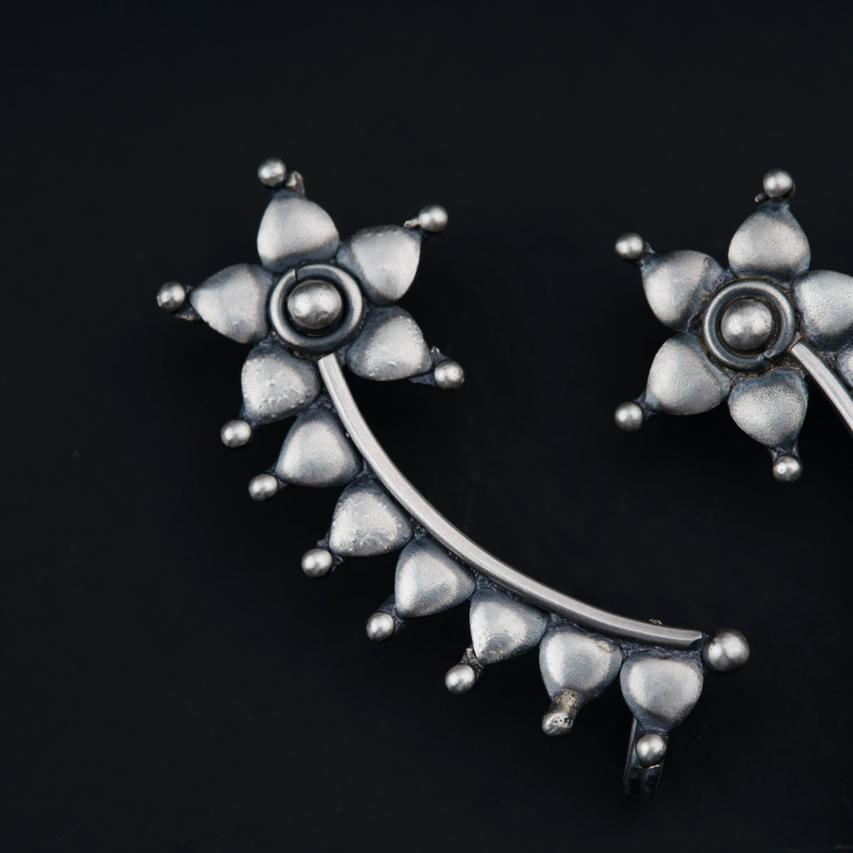 a pair of silver colored earrings on a black background