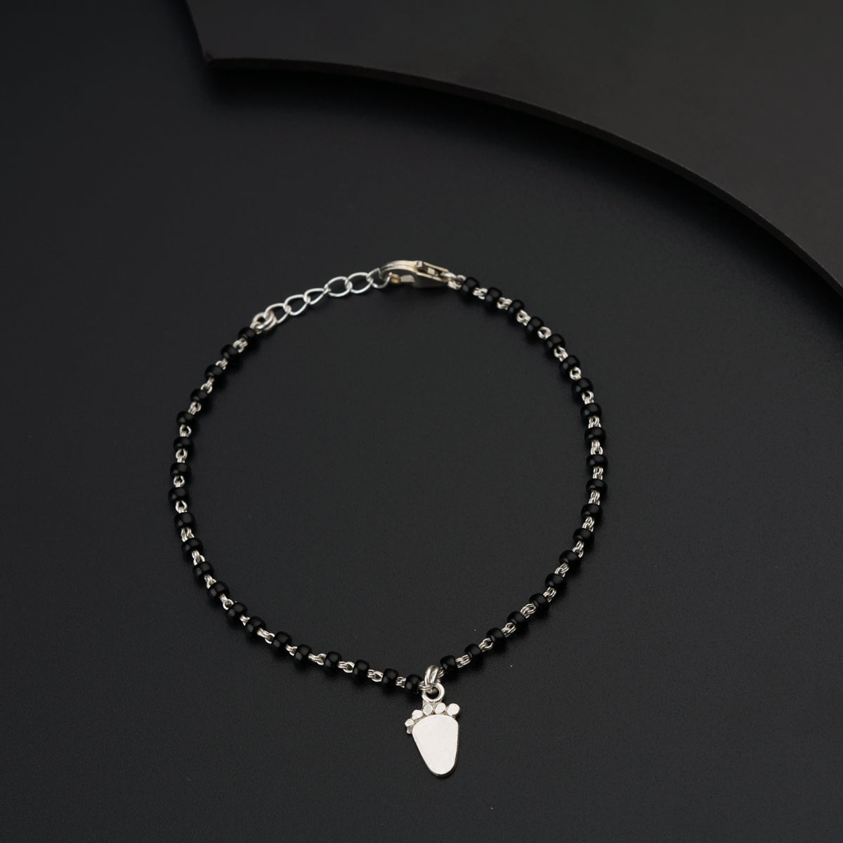 a black beaded bracelet with a silver charm