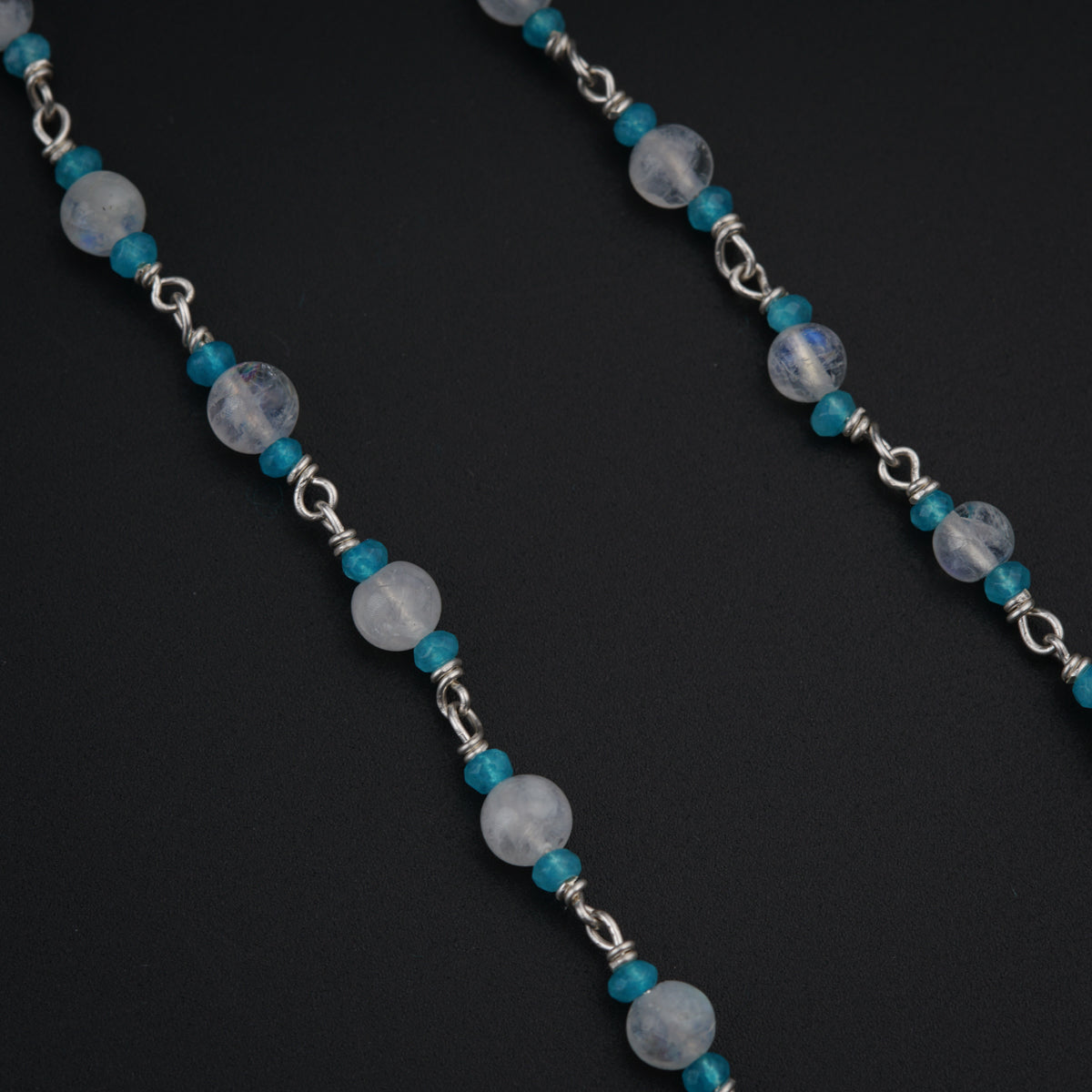 a blue and white beaded necklace on a black background